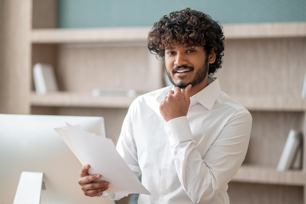 オフィスで白いシャツを着た若いインド人男性