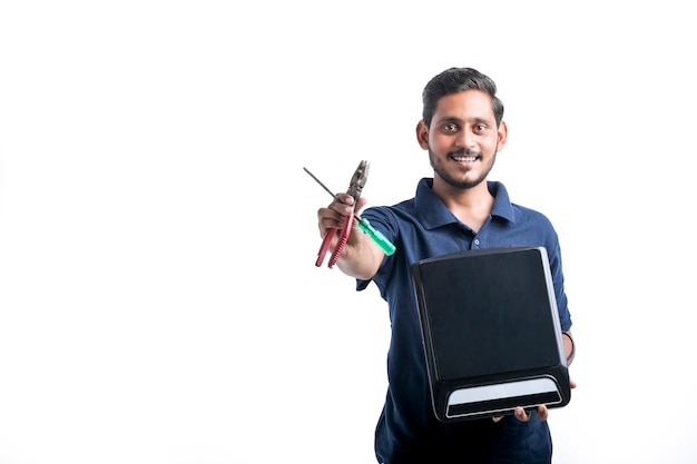 Young indian man who repair electronics kitchenware holding tools and electric stove in hand