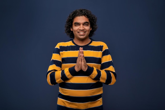 Young Indian man with welcome expression or inviting or greeting Namaste on dark background