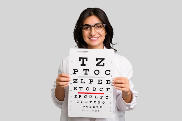 Young indian oculist woman holding an eye chart paper cut out isolated