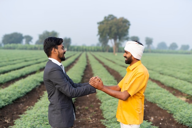 Young indian officer shake hand with farmer at field