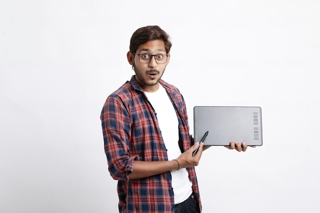 Молодой индийский профессиональный дизайнер показывает графический планшет с цифровой ручкой