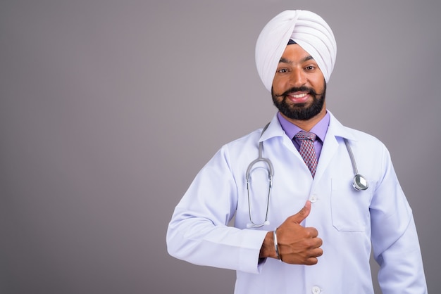 Young Indian Sikh man doctor smiling and giving thumb up