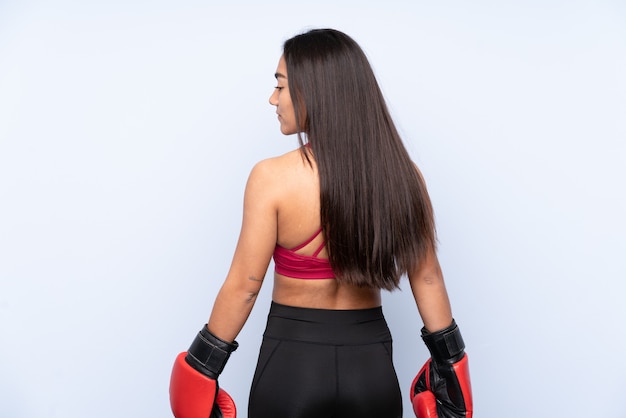 Young Indian sport woman isolated on blue background with boxing gloves