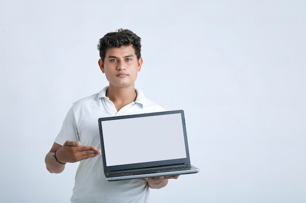 Young indian successful man showing laptop screen over white background.