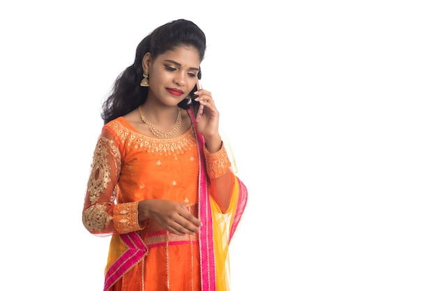 Young Indian traditional girl using a mobile phone or smartphone on white