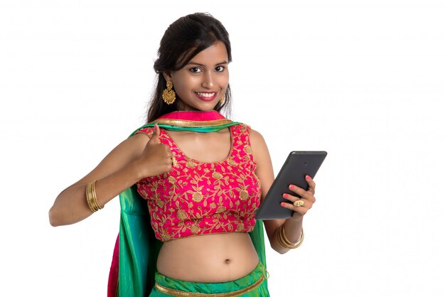 Young Indian traditional woman using a mobile phone or smartphone isolated on a white wall