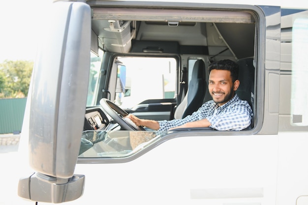 Young indian truck driver sitting behind steering wheel in a cabin