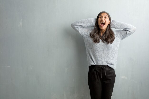 Young indian woman against a grunge wall surprised and shocked, looking with wide eyes