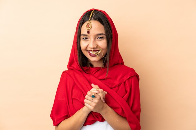 Young Indian woman on beige wall laughing