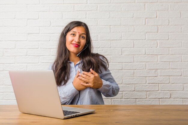 Young indian woman doing a romantic gesture, in love with someone or showing affection for some friend. Wearing a headset.