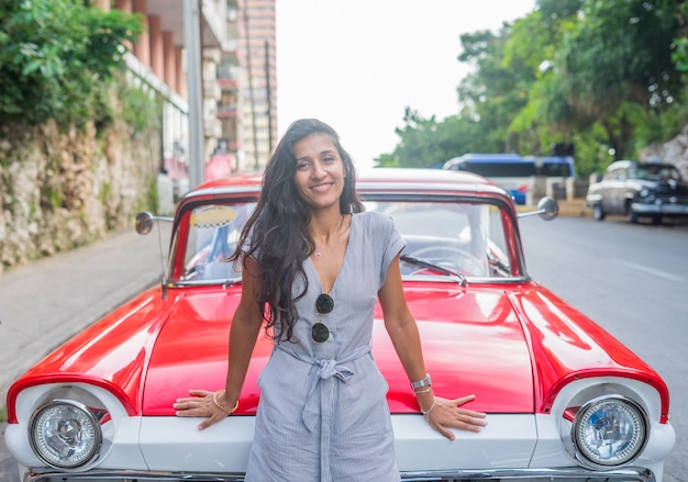 Young indian woman happy in front of a red car