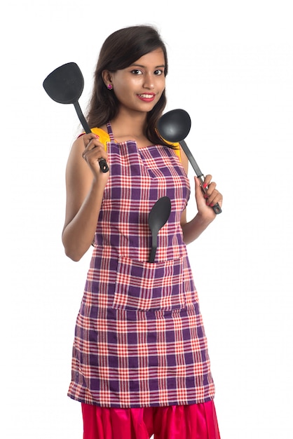 Young Indian woman holding kitchen utensil (spoon, stapula, ladle, and pan, etc.) on a white background