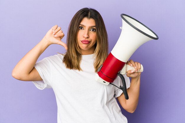 Young indian woman holding a megaphone isolated showing a dislike gesture, thumbs down. Disagreement concept.