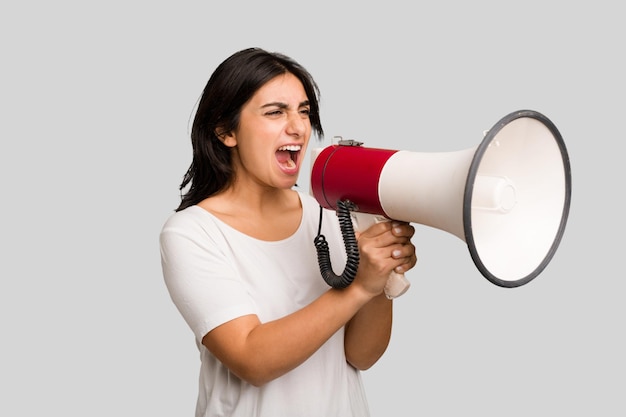 Young Indian woman holding a megaphone isolated