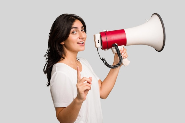 Young Indian woman holding a megaphone isolated