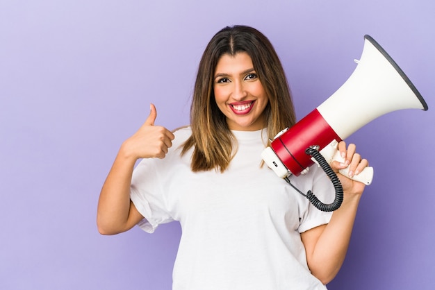 Young indian woman holding a megaphone smiling and raising thumb up