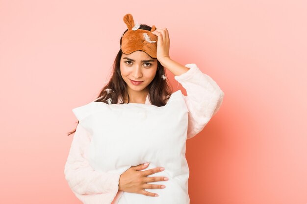 Young indian woman holding a pillow isolated being shocked, she has remembered important meeting.