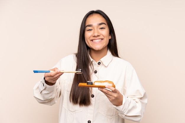 Young Indian woman holding sushi isolated on beige background