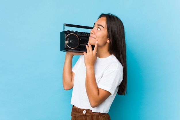 Young indian woman holding a vintage cassete isolated