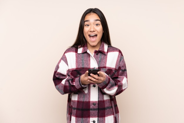 Young Indian woman isolated on beige surprised and sending a message