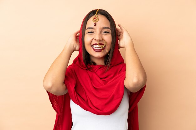 Young Indian woman isolated on beige wall laughing