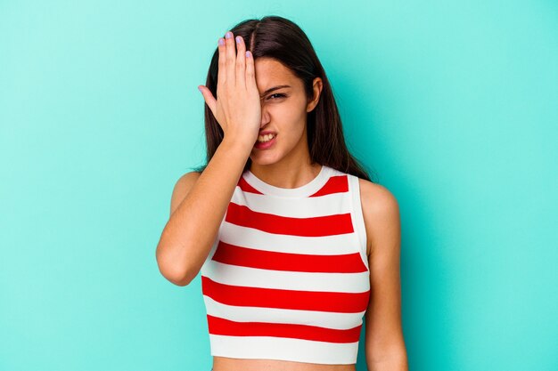 Young Indian woman isolated on blue background forgetting something, slapping forehead with palm and closing eyes.