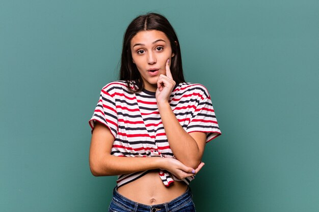 Young Indian woman isolated on blue background having some great idea, concept of creativity.