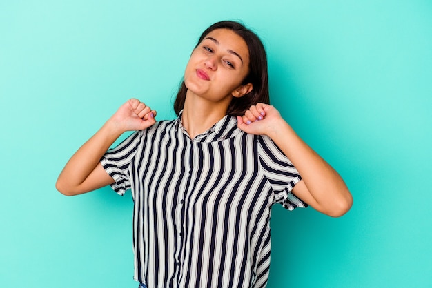 Young Indian woman isolated on blue background stretching arms, relaxed position.