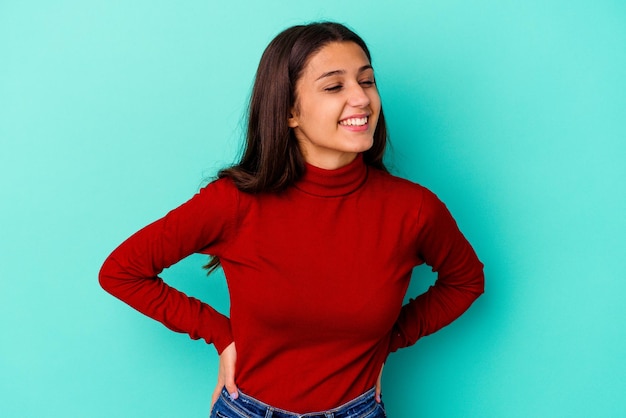 Young Indian woman isolated on blue confident keeping hands on hips.