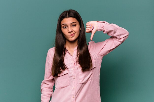 Young Indian woman isolated on blue wall showing thumb down, disappointment concept