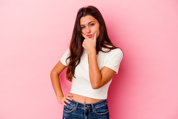 Young Indian woman isolated on pink background contemplating, planning a strategy, thinking about the way of a business.