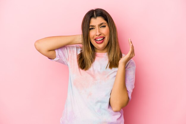 Young indian woman isolated on pink background screaming with rage.