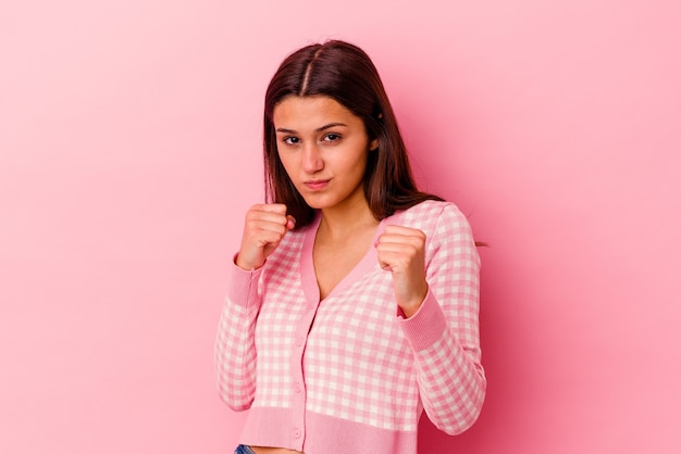 Young Indian woman isolated on pink background showing fist to camera, aggressive facial expression.