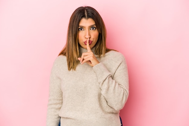 Young indian woman isolated on pink background thinking and looking up, being reflective, contemplating, having a fantasy.