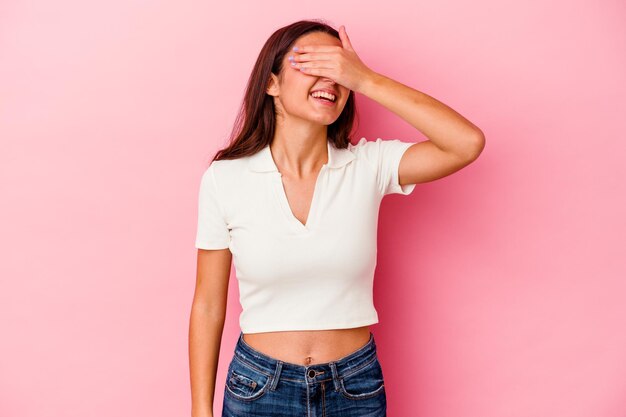 Young Indian woman isolated on pink laughs joyfully keeping hands on head