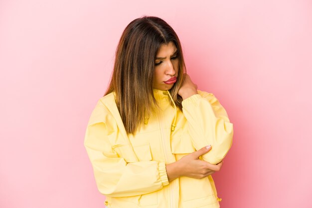 Young indian woman isolated on pink space massaging elbow, suffering after a bad movement.