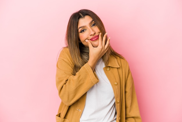 Young indian woman isolated on pink wall doubting between two options