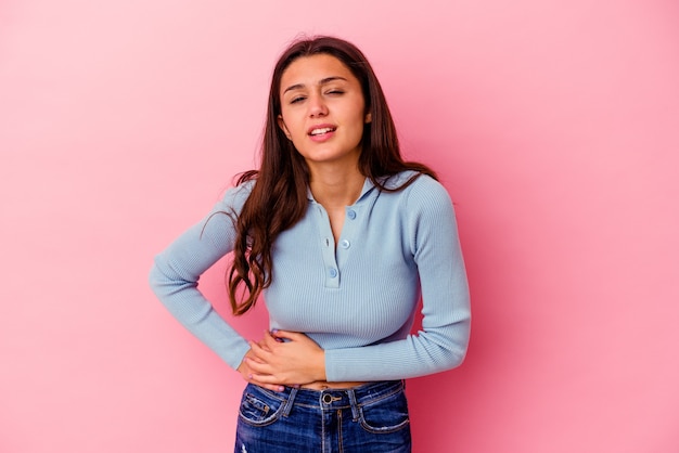 Young Indian woman isolated on pink wall having a liver pain, stomach ache.