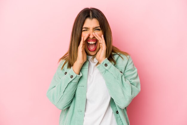 Young indian woman isolated on pink wall shouting excited to front.