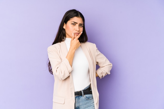 Young indian woman isolated on purple background contemplating, planning a strategy, thinking about the way of a business.