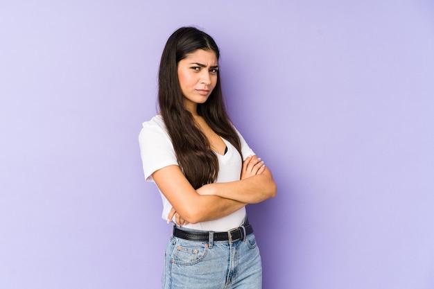 Young indian woman isolated on purple background frowning face in displeasure, keeps arms folded.