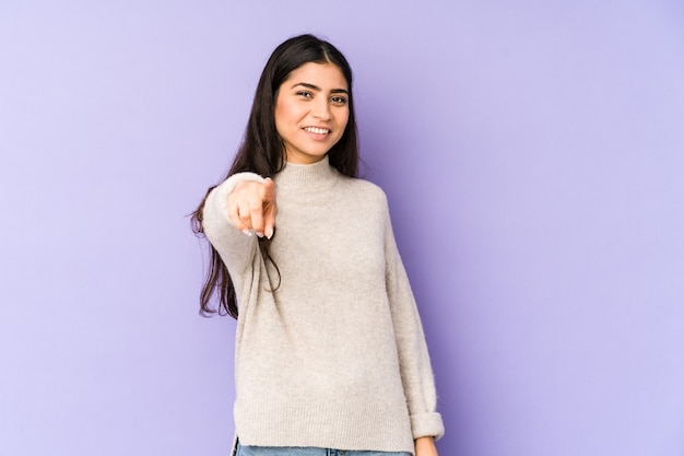 Young indian woman isolated on purple background pointing to front with fingers