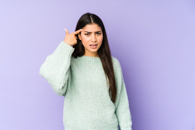 Young indian woman isolated on purple background showing a disappointment gesture with forefinger.