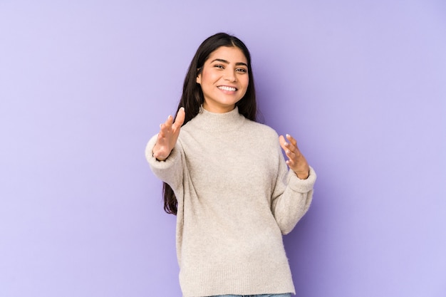 Young indian woman isolated on purple feels confident giving a hug