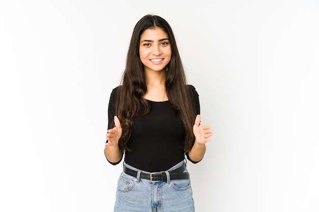 Young indian woman isolated on purple holding something with both hands, product presontation.