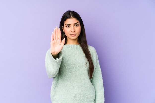 Young indian woman isolated on purple standing with outstretched hand showing stop sign, preventing you.