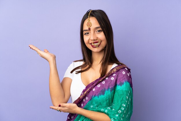来て招待する側に手を拡張する紫色の壁に分離された若いインド人女性