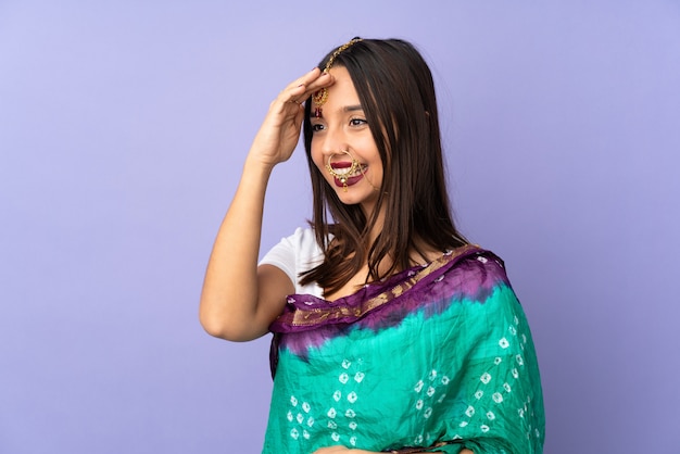 Foto giovane donna indiana isolata sulla parete viola che saluta con la mano con l'espressione felice