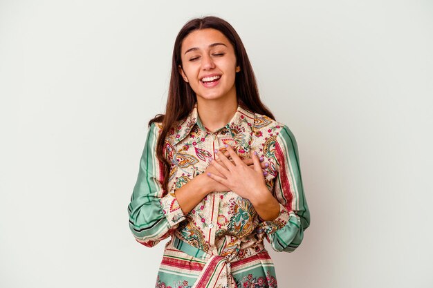 Young Indian woman isolated on white laughing keeping hands on heart, concept of happiness.